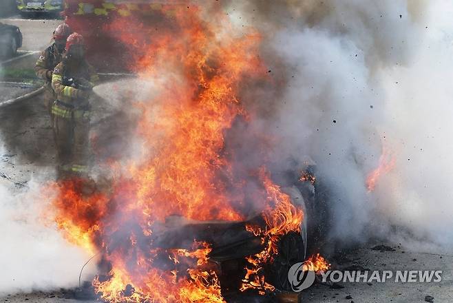 쉽게 꺼지지 않는 전기자동차 화재 지난 7월 경기도 용인시 경기도소방학교에서 열린 '전기자동차 실화재 진압 시연회'에서 소방관들이 진화작업을 하고 있다. [연합뉴스 자료사진]