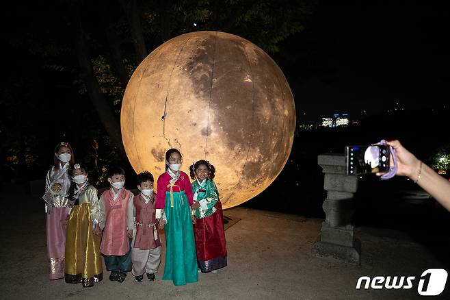 서울 종로구 창경궁 풍기대에 설치된 대형 보름달 앞에서 아이들이 한복을 입고 사진을 찍고 있다. ⓒ News1 이승배 기자