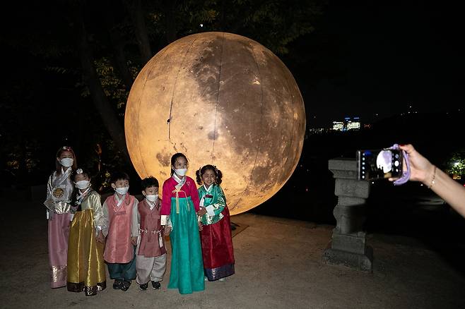 서울 종로구 창경궁 풍기대에 설치된 대형 보름달 앞에서 아이들이 한복을 입고 사진을 찍고 있다./뉴스1