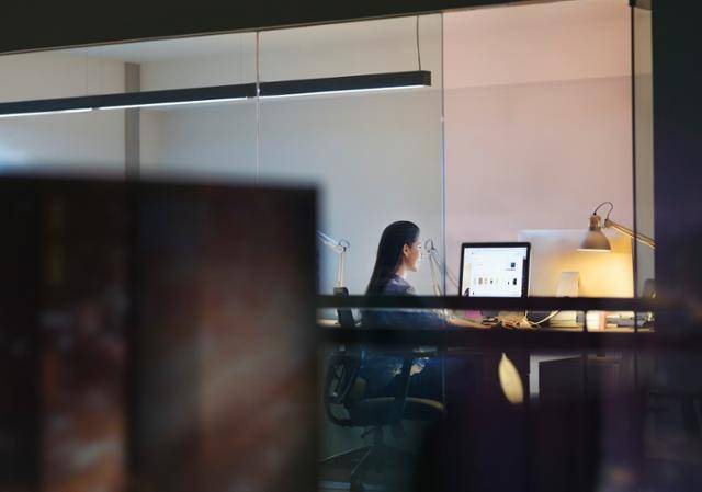 어두운 사무실에서 한 여성이 컴퓨터로 업무를 하고 있다. 게티이미지뱅크