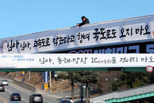 2020년 9월 9일 강원 동해시가 설 연휴 코로나19가 확산하는 것을 막기 위해 국도 주변에 고향에 오는 것을 자제해 달라는 현수막을 내걸고 있다. (위) 시는 지난 8일 고속도로 진출입로 주변에도 비슷한 내용의 현수막을 선보였다. 동해=연합뉴스