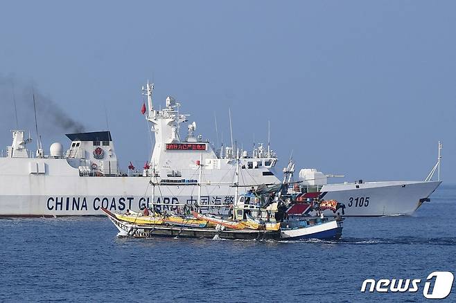 지난 20일(현지시간) 남중국해(서필리핀해) 스카버러 암초(중국명 황옌다오·필리핀명 바조데마신록) 인근에서 조업하는 필리핀 어선 옆으로 중국 해안경비대 함정이 지나가고 있다. 2023.9.25. ⓒ AFP=뉴스1 ⓒ News1 김기성 기자