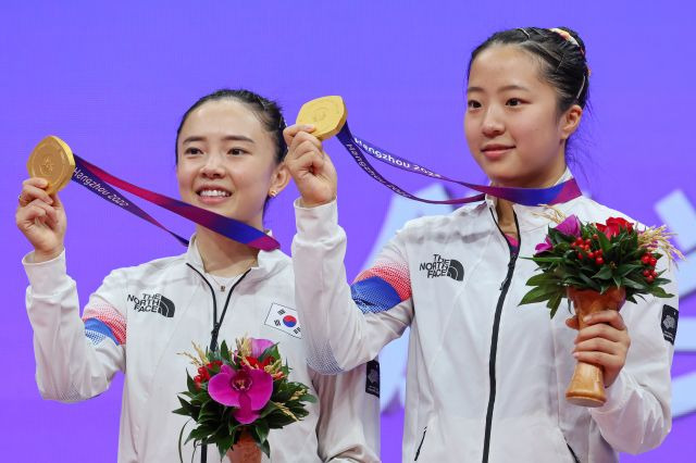 2일 중국 항저우 궁수 캐널 스포츠파크 체육관에서 열린 19회 항저우 아시안게임 탁구 여자 복식에서 금메달을 딴 한국 신유빈-전지희가 시상대에 올라 메달을 들어올려 보이고 있다. 연합뉴스