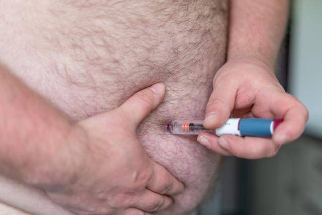 한 남성이 주사형 비만 치료제를 배에 주입하고 있다. 덴마크 기업 노보 노디스크의 비만 치료제 위고비는 최근 전 세계의 신드롬을 불러일으키고 있다. 그만큼 비만이 전 세계의 관심이라는 뜻으로 풀이된다. 게티이미지뱅크