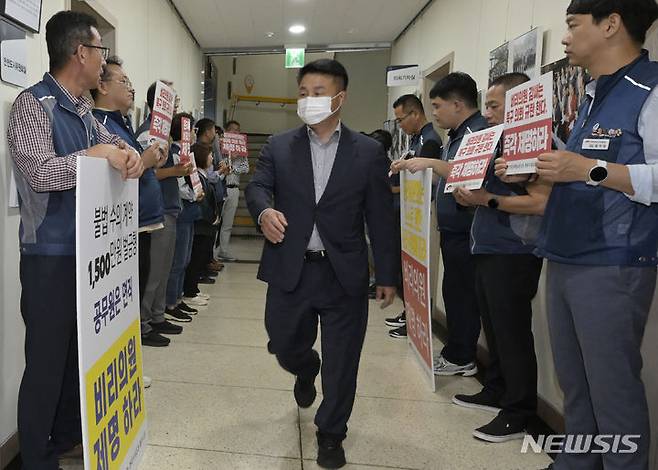 [광주=뉴시스] 변재훈 기자 = 계약 비위로 벌금형 선고를 받은 기대서 광주 북구의원이 4일 광주 북구의회 윤리특별위원회 회의실에 들어서고 있다. 회의실 앞 복도에서 공무원 노조 조합원 등이 손팻말 규탄 시위를 하고 있다. 2023.10.04. wisdom21@newsis.com