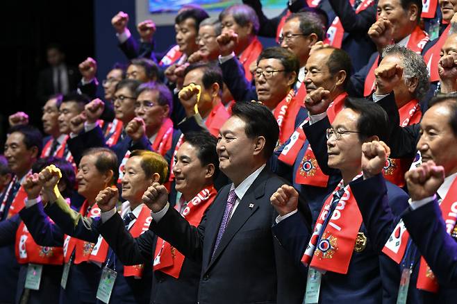 윤석열 대통령이 4일 서울 송파구 올림픽공원 올림픽홀에서 열린 향군 창설 제71주년 기념식 및 전국 읍·면·동 회장 총력안보 결의대회에서 참석자들과 함께 기념 촬영을 하며 구호를 외치고 있다. 연합뉴스