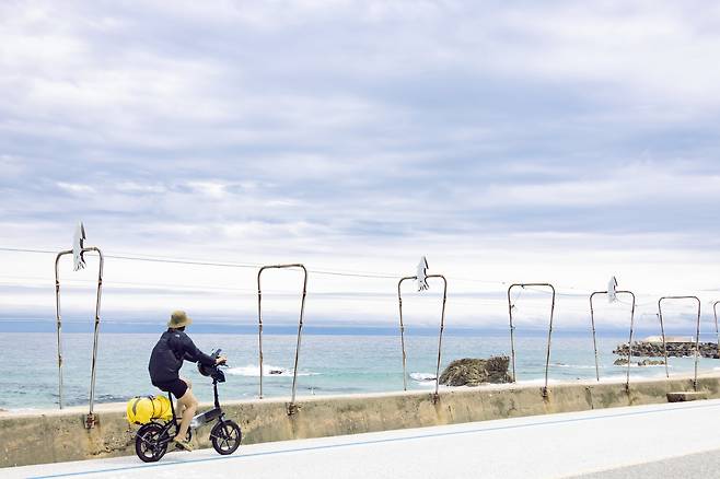 울진군 오징어풍물거리를 지나치는 자전거 여행자들  [사진/성연재 기자]