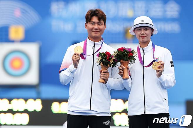 이우석과 임시현이 4일 중국 항저우 푸양 인후 스포츠센터 양궁장에서 열린 2022 항저우 아시안게임 양궁 리커브 혼성전 시상식을 마친 후 취재진을 향해 금메달을 들어보이고 있다. 이우석과 임시현은 이날 결승에서 일본의 노다 사츠키-후루카와 다카하루에게 6-0 완승을 거두고 금메달을 차지했다. 2023.10.4/뉴스1 ⓒ News1 유승관 기자