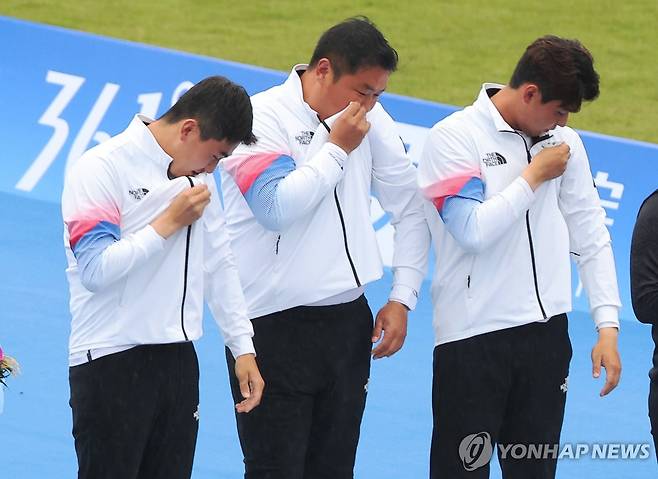 태극기에 입맞추며! (항저우=연합뉴스) 홍해인 기자 = 6일 중국 항저우 푸양 인후 스포츠센터에서 열린 2022 항저우 아시안게임 양궁 리커브 남자 단체전 결승에서 승리해 금메달을 획득한 한국  김제덕, 오진혁, 이우석이 시상대에 오르며 유니폼 태극기에 입맞추고 있다. 2023.10.6 ondol@yna.co.kr