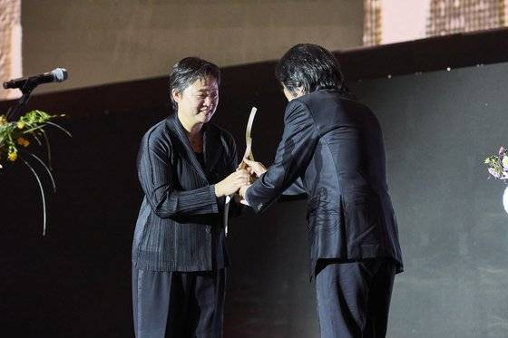 4일 열린 제28회 부산국제영화제 개막식에서 고 윤정희 배우를 대신해 한국영화공로상을 받은 딸 백진희 씨.마지막 작품 '시'를 각본ㆍ연출한 이창동 감독이 시상했다. 사진 부산국제영화제