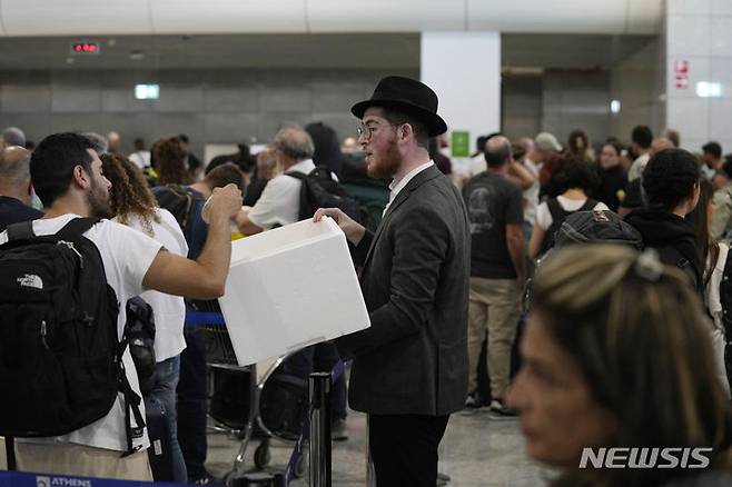 [아테네(그리스)=AP/뉴시스]그리스 아테네의 엘레프테리오스 베니젤로스 국제공항에서 10일 한 남성이 이스라엘행 항공기에 탑승하기 위해 줄을 서 기다리고 있는 승객들에게 샌드위치를 나눠주고 있다. 지난 7일 하마스의 대규모 기습 공격으로 1200명이 넘는 이스라엘인들이 사망한 것으로 전해지는 가운데 아테네에서부터 뉴욕에 이르기까지 해외에 거주하는 이스라엘인들은 이스라엘로 돌아가기 위해 안간힘을 쓰고 있다. 이스라엘로 향하는 항공편들이 속속 운항을 중단하는 상황에서 이들은 공항으로 달려가 이스라엘행 항공기에 탑승할 수 있는 방법을 찾기 위해 도움을 요청하고 있다. 2030.10.11.