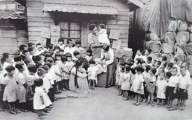 한국보육원을 방문해 선물을 나눠주며 위문하는 미군들. 사진 가운데 쪽진 머리를 한 여성이 황온순 원장.(미국 국립문서기록관리청, NARA)