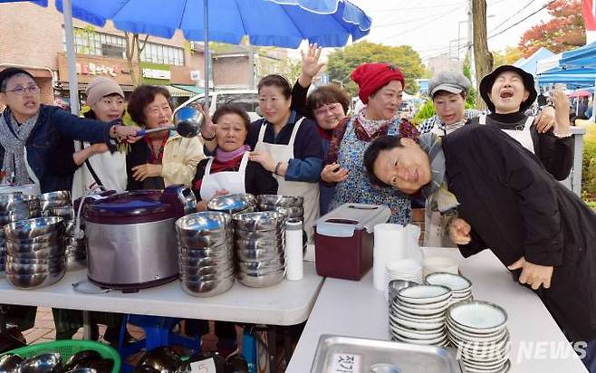 "나눔은 행복"성북동성당 주임 김형목 신부(사진 오른쪽)가 익살스러운 몸짓으로 성당에서 운영하는 음식 판매 부스에서 교인들과 기념촬영을 하고 있다.