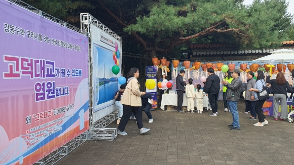 13일 서울 강동구에서 열린 강동선사문화축제에 마련된 고덕대교 명명 기원 소망벽에 주민들이 엽서를 붙이고 있다. 강동구 제공