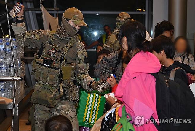 지난 13일 공군 공정통제사들이 공군 KC-330 탑승에 앞서 우리 교민들에게 필요한 물품을 나눠주는 모습 [연합뉴스 자료사진]