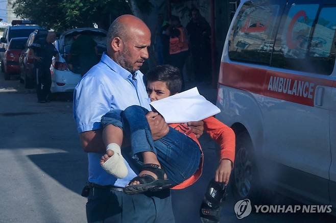 가자지구에서 다친 아이 옮기는 팔레스타인인 [AFP=연합뉴스]