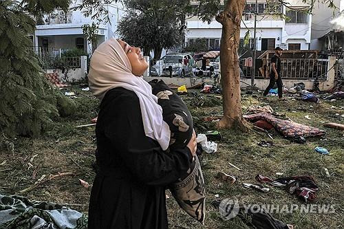 (가자 지구 AFP=연합뉴스) 18일(현지시간) 한 팔레스타인 여성이 전날 밤 폭격을 당한 가자 지구 내 알아흘리 병원에서 망연자실하게 서 있다. 2023.10.18.