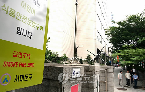 서울 서대문구의 한 초등학교 정문에 세워진 ‘금연구역’ 표지판 앞으로 한 사람이 담배를 피우며 지나가고 있다.[사진 = 연합뉴스]