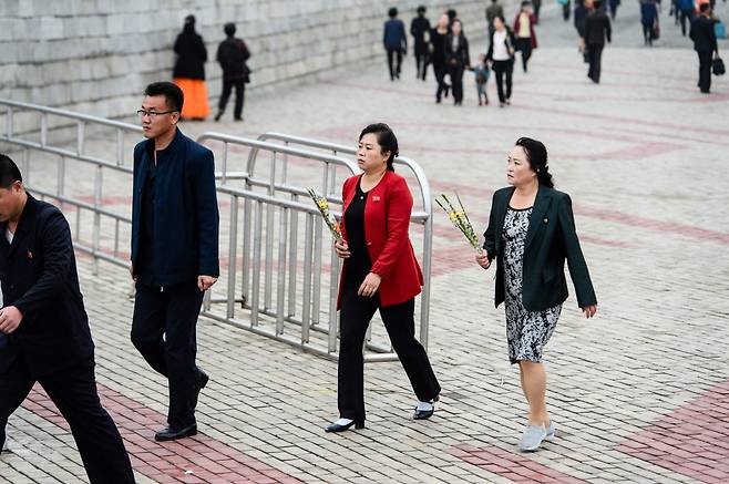 미국 법무부는 18일(현지 시각) 북한의 정보기술(IT) 노동자들이 해외 기업에 위장 취업하는데 쓴 웹사이트 도메인 17개를 압류했다고 밝혔다. 사진은 북한 조선노동당 창당 78주년인 지난 10월10일 평양 시민들이 만수대언덕에 있는 김일성 주석과 김정일 국방위원장 동상에 헌화하기 위해 작은 꽃다발을 들고 걸어가고 있는 모습 ⓒAFP=연합뉴스