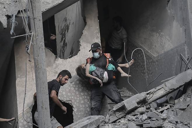 지난 10월 19일(현지시간) 이스라엘군의 폭격을 받은 팔레스타인 가자지구 남부 칸 유니스 지역의 건물에서 한 아이가 구조돼 나오고 있다. / 연합뉴스