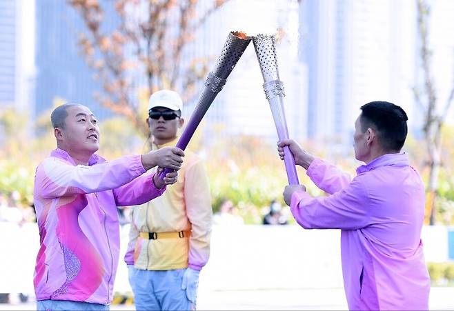 김진혁(왼쪽) 항저우장애인아시아게임 한국선수단장은 21일 중국 항저우 신도심에 위치한 민샹로에서 성화를 봉송하고 있다. 대한장애인체육회 제공