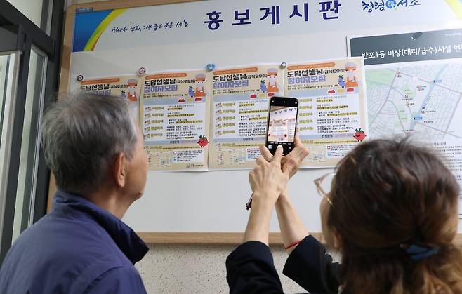 지난 19일 서울 서초구 반포1동 주민센터 민원실 입구의 홍보 게시판에 급식 도우미 모집 공고가 붙었다. 이곳을 지나던 어르신들이 공고 내용을 살펴보고 있다. 온라인 구직 정보는 어르신들이 일자리 정보를 얻기에는 아직까지 문턱이 높다./전기병 기자