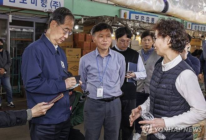 한덕수 국무총리가 24일 오후 농수산물 물가 점검을 위해 서울 마포구 마포농수산물시장을 찾아 김치 양념 전문 상점을 찾아 상인이 이야기 하는 현장 상황을 수첩에 적고 있다. ⓒ연합뉴스