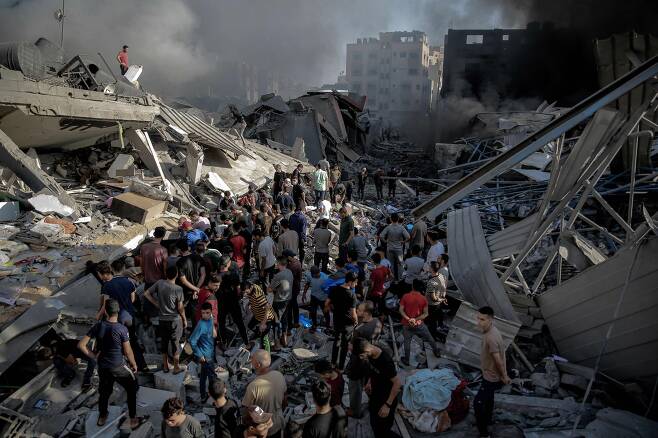 26일(현지 시각) 팔레스타인 가자지구에서 주민들이 이스라엘 공습으로 파괴된 건물 주위에 모여있다. 지난 7일 팔레스타인 무장 정파 하마스가 이스라엘을 공격해 교전이 벌어진 뒤 양측에서 7000명 이상이 사망했다./AFP 연합뉴스