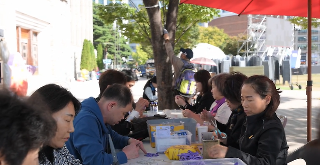 이태원 참사 유가족들이 서울시청 앞 분향소에서 보라색 리본을 만들고 있는 모습