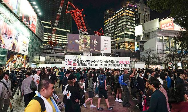 지난 27일 ‘시부야는 핼러윈 이벤트 장소가 아니다’라는 대형 입간판이 세워진 일본 도쿄 시부야역 앞을 지나는 사람들이 평소 때와 다름없이 각자의 목적지를 향해 가고 있다. 도쿄=EPA연합뉴스