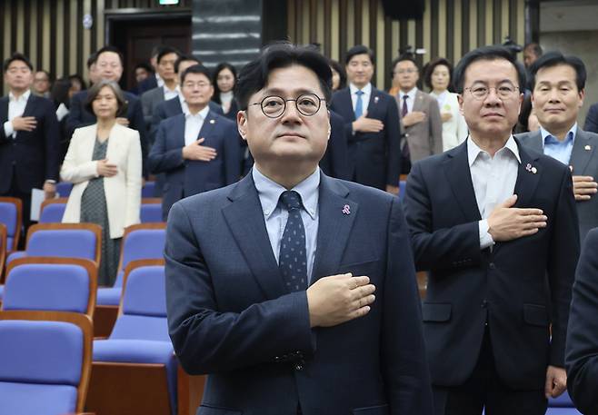 홍익표 더불어민주당 원내대표를 비롯한 의원들이 30일 국회에서 열린 의원총회에서 국기에 경례하고 있다.  연합뉴스