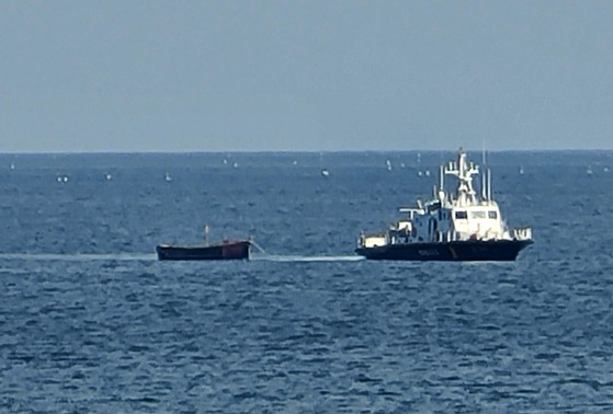 The South Korean military tows a small wooden boat that carried four North Korean defectors who crossed the Northern Limit Line (NLL) in the East Sea on Oct. 24. [YONHAP]