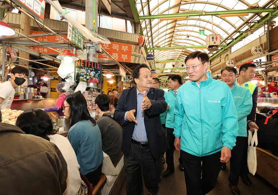 Hana Bank CEO Lee Seung-lyul, right, talks with a merchant at a traditional market in Seoul on Friday. [HANA BANK]