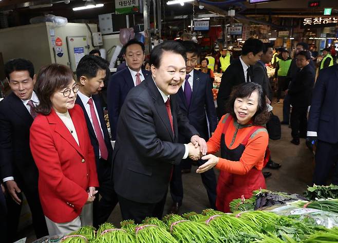 [대구=뉴시스] 조수정 기자 = 윤석열 대통령이 7일 대구 북구 칠성종합시장을 방문, 미나리를 판매하는 상인과 악수하고 있다. (대통령실통신사진기자단) 2023.11.07.