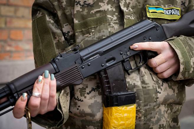 지난해 2월 우크라이나 키이우에서 무장한 우크라이나 여성이 칼라니시코프 소총을 들고 거리 순찰을 도는 모습./ AP연합뉴스