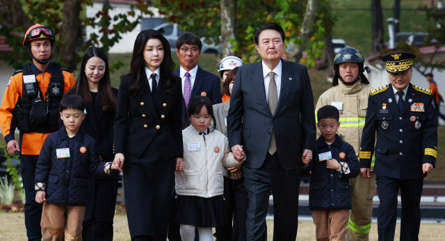 윤석열 대통령과 김건희 여사가 9일 서울 용산어린이정원 잔디마당에서 열린 제61주년 소방의 날 기념식에 순직 소방관 자녀들의 손을 잡고 입장하고 있다. 대통령실통신사진기자단=연합뉴스