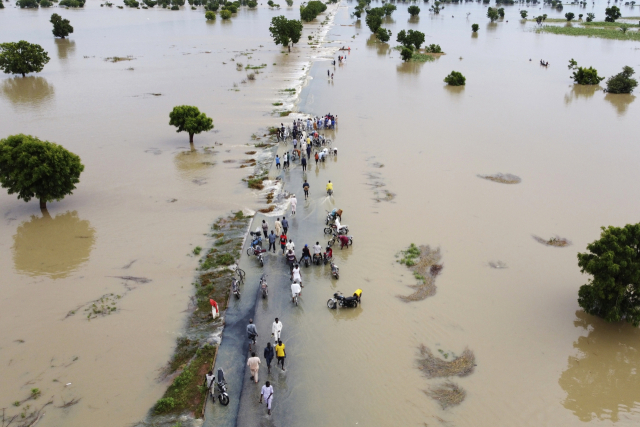 ▲ 2022년 9월 19일 나이지리아 하데자에서 폭우가 내린 후 사람들이 홍수 속을 걷고 있다. 이 홍수의 원인은 기후 변화로 지목됐다. ⓒAP=연합뉴스