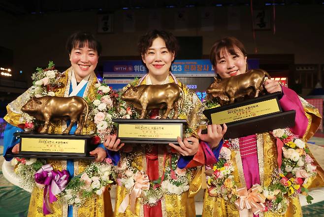 15일 경남 고성군 고성군국민체육센터에서 열린 '위더스제약 2023 천하장사 씨름대축제' 여자부 개인전에서 장사에 등극한 선수들이 황소 트로피를 들고 기념 촬영하고 있다. 왼쪽부터 양윤서 장사, 김은별 장사, 김주연 장사. 대한씨름협회