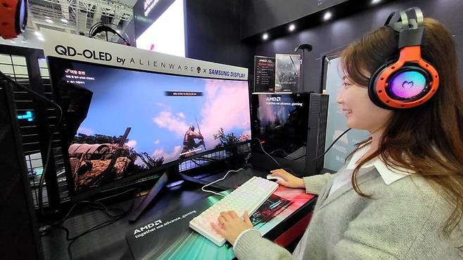 삼성디스플레이 모델이 16일 지스타 2023 AMD 부스에 전시된 '에일리언웨어 34 커브드 QD-OLED 게이밍 모니터'로 대규모 이용자 간 대전 '워헤이븐'을 체험하고 있다. 삼성디스플레이 제공