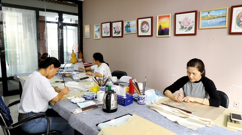 Women are engaged in daily practice of painting skills at the workshop.