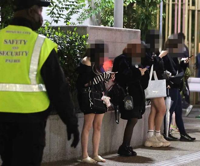 어느 늦은 밤, 일본 도쿄 오쿠보공원 앞에서 젊은 여성들이 휴대전화를 보면서 나란히 서 있다./석간후지