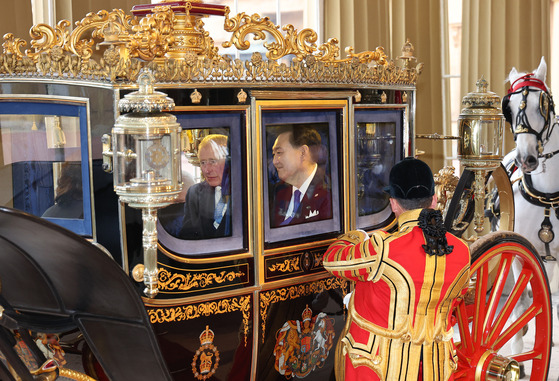 Korean President Yoon Suk Yeol, right, and King Charles III arrive by carriage at Buckingham Palace in London Tuesday following a welcome ceremony at Horse Guards Parade. [JOINT PRESS CORPS]