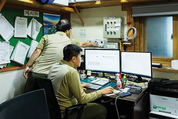 대피소 사무 공간에서 분주한 근무자들. 근무자들은 대피소 '관리'만 하지 않는다. 본소에 전달할 각종 보고서 작성도 그들의 임무다. 매우 바쁘다.