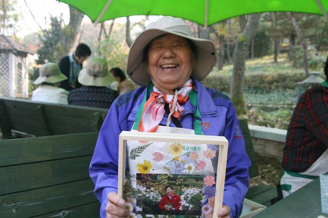 한 어르신이 말린 꽃으로 액자를 만들어 환하게 웃고 있다. 신구대 식물원 제공