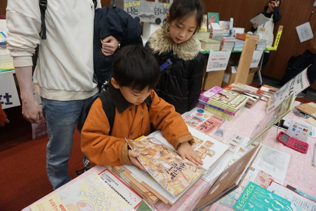 26일 도쿄 진보초에서 열린 한국 서적 축제 'K-북 페스티벌 인 재팬'에 참가한 한 어린이가 일본어로 번역된 한국 그림책을 손으로 짚으며 읽고 있다. 도쿄=최진주 특파원