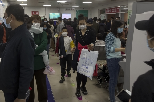 중국 부모가 30일 마스크를 쓴 아이의 손을 잡고 혼잡한 어린이 병원을 빠져나오고 있다. 최근 중국에서 호흡기 질환이 증가하자 보건 당국은 새로운 바이러스에 의한 것이 아니라고 밝혔다.  베이징 AP 연합뉴스