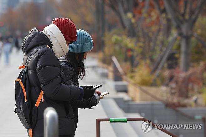 추위 속 관광 (서울=연합뉴스) 신현우 기자 = 전국 아침 기온이 영하권으로 떨어진 26일 오전 서울 광화문광장을 찾은 관광객들이 광화문 육조거리 관련 안내판을 스마트폰으로 촬영하고 있다. 2023.11.26 nowwego@yna.co.kr