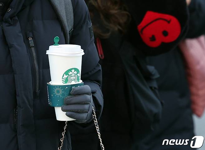 전국 대부분 지역의 아침 기온이 영하권으로 떨어지며 올 가을 들어 가장 추운 30일 오전 서울 광화문네거리에서 따뜻한 커피와 방한 용품을 착용한 한 시민이 출근하고 있다. 2023.11.30/뉴스1 ⓒ News1 김진환 기자