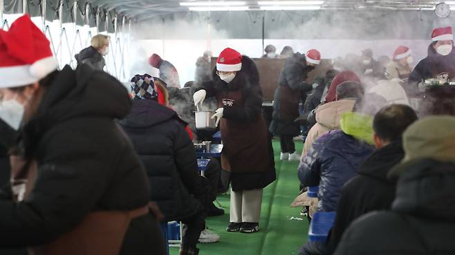 성탄절 다음날인 2021년 12월 26일 명동밥집에서 산타 모자를 쓴 봉사자들이 '손님'들에게 식사를 대접하고 있다. /고운호 기자