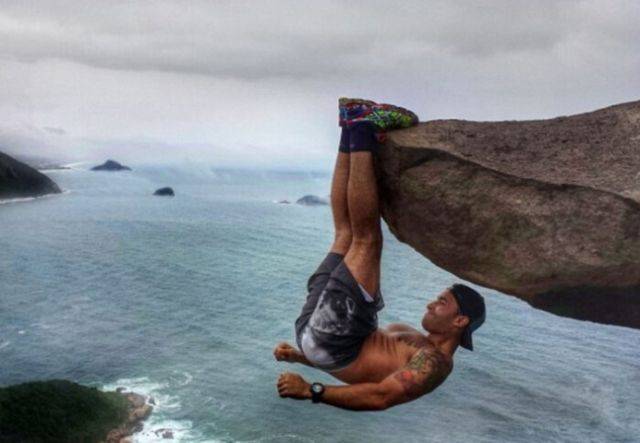브라질의 보디빌더 루이스 페르난도 칸델라가 300m 높이 해안 절벽에 거꾸로 매달려 있다. 사진=데일리메일 캡쳐